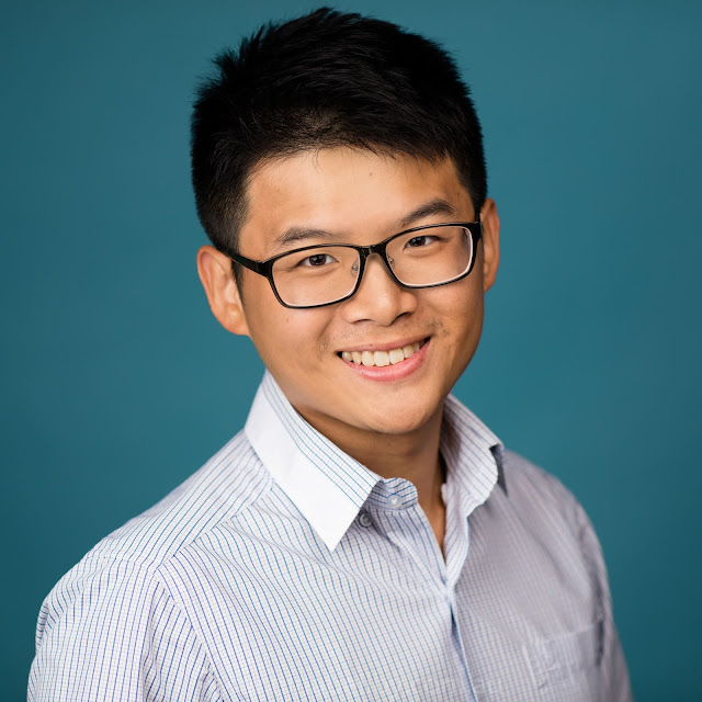 Headshot of a young Asian man on a blue background