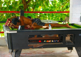 A man who is sleeping on a snooker billiard table. A man who is sleeping on a snooker billiard table.