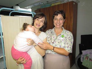 À direita a Dra. Lenise Garcia em visita a Joana Schmitz Croxato, que tem ao colo a pequena filha Vitória, nascida com má formação cerebral.
