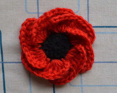 "Hope Bloom" poppy after steam blocking. The pins have been removed and the red petals are now open and the black centre is visible.