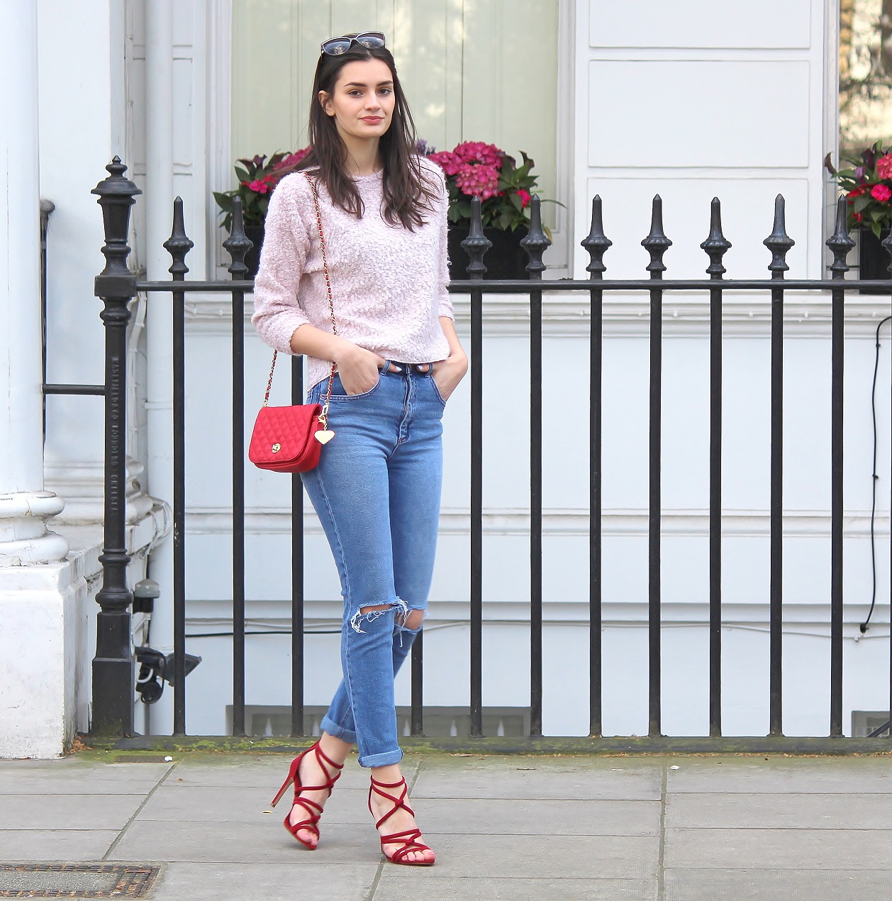 peexo fashion blogger wearing pink fluffy jumper and ripped mom jeans and red strappy heels and red small bag in spring