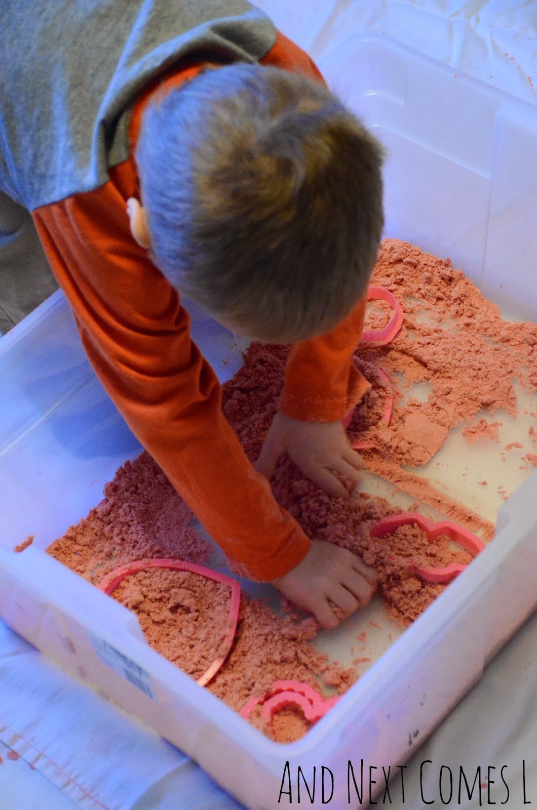 Digging in cinnamon heart cloud dough for Valentine's Day sensory play from And Next Comes L