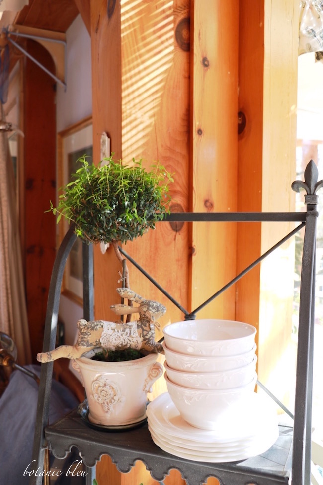 french-style-plant-stand-holds-white-dishes-and-plants