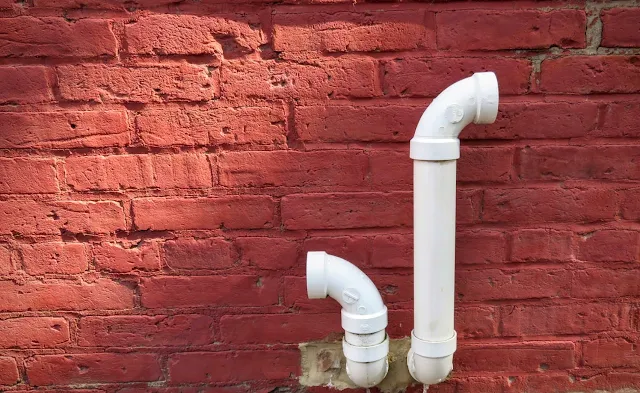 White pipes against a red brick wall in the Mexican War Streets Neighborhood of Pittsburgh