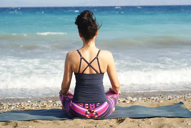 woman on beach doing self care meditation 