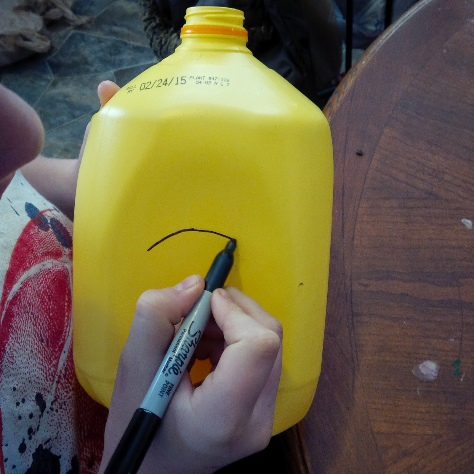 using marker to make holes for the milk jug bird feeder