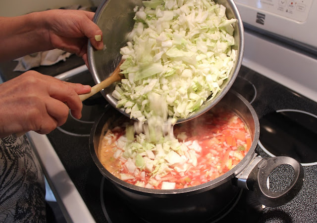 adding chopped cabbage to pot of borscht