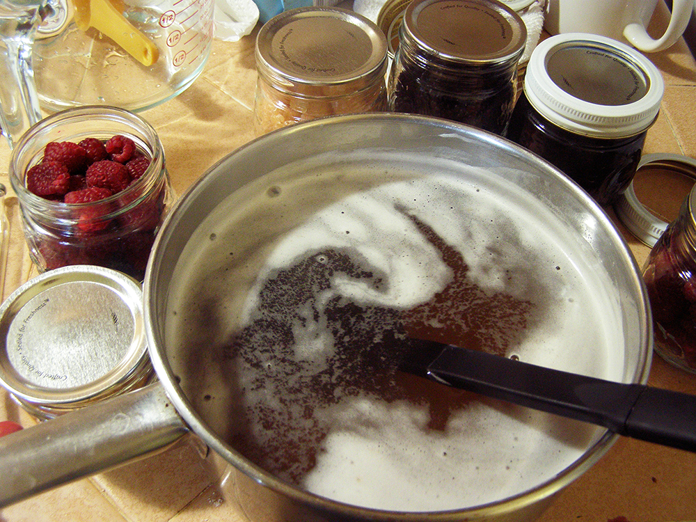 Pan of Heated Honey Sauce with Jars of Berries