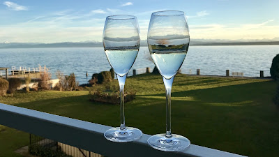 Twee glazen op de railing van het balkon en uitzicht op het water.