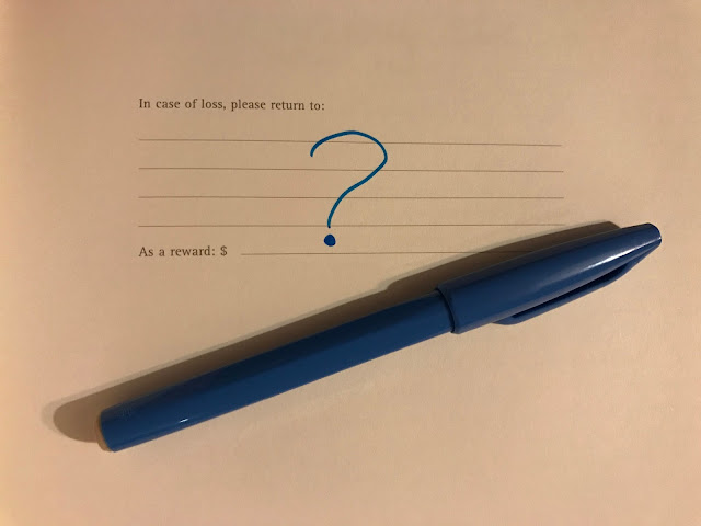 The inside page of a moleskine notepad which reads "In case of loss, please return to:" with a felt tip drawn ? And a blue pen