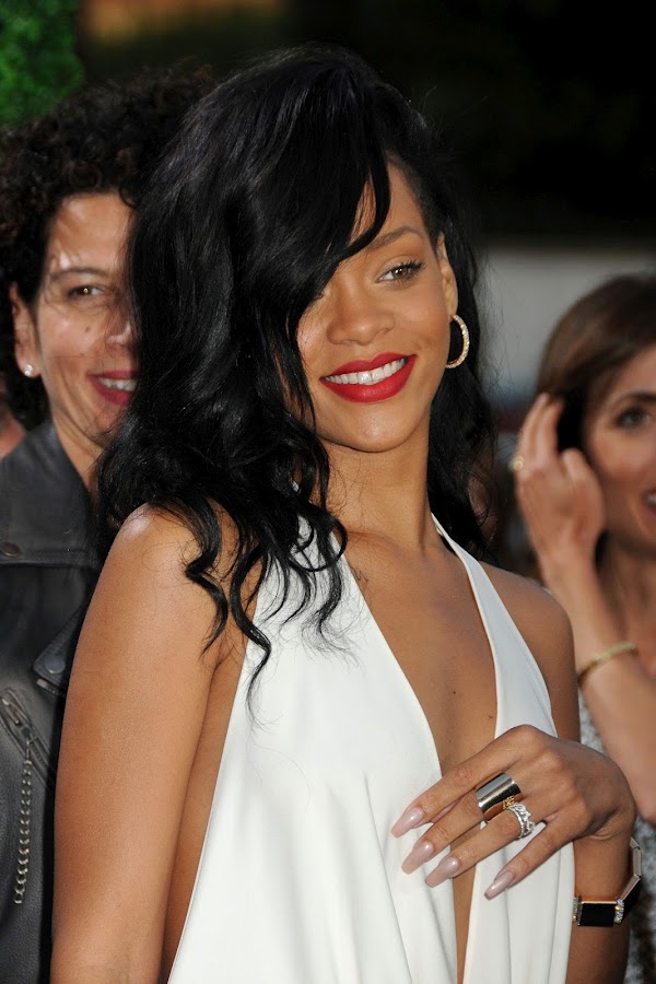 Rihanna smiles for paparazzi in a sexy white dress