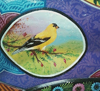 painting of yellow bird scene in a black circle painted onto decorated car