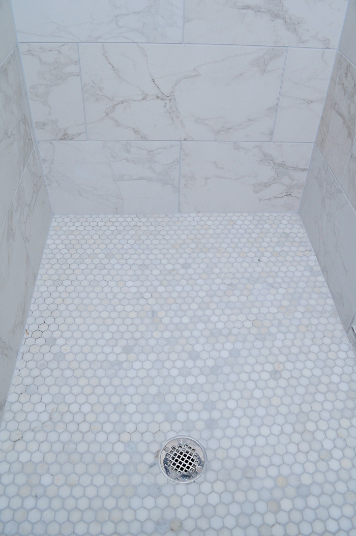 Regrets from our new construction home in Corpus Christi Marble hex tile shower floor paired with marble look tile in a master bathroom.