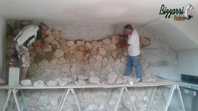 Bizzarri fazendo o revestimento de pedra, com pedra moledo, sendo o revestimento com pedra na parede da adega da residência em Itatiba-SP com essa pedra moledo na cor bege com espessura de 15 a 20 cm.