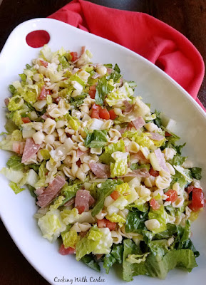 This chopped salad is perfect for a party! It is part pasta salad, part green salad and all yum! A simple dressing and all of your favorite ingredients will be great for dinner, a potluck or a BBQ! large platter of salad with pasta, cheese, meats, tomatoes etc.