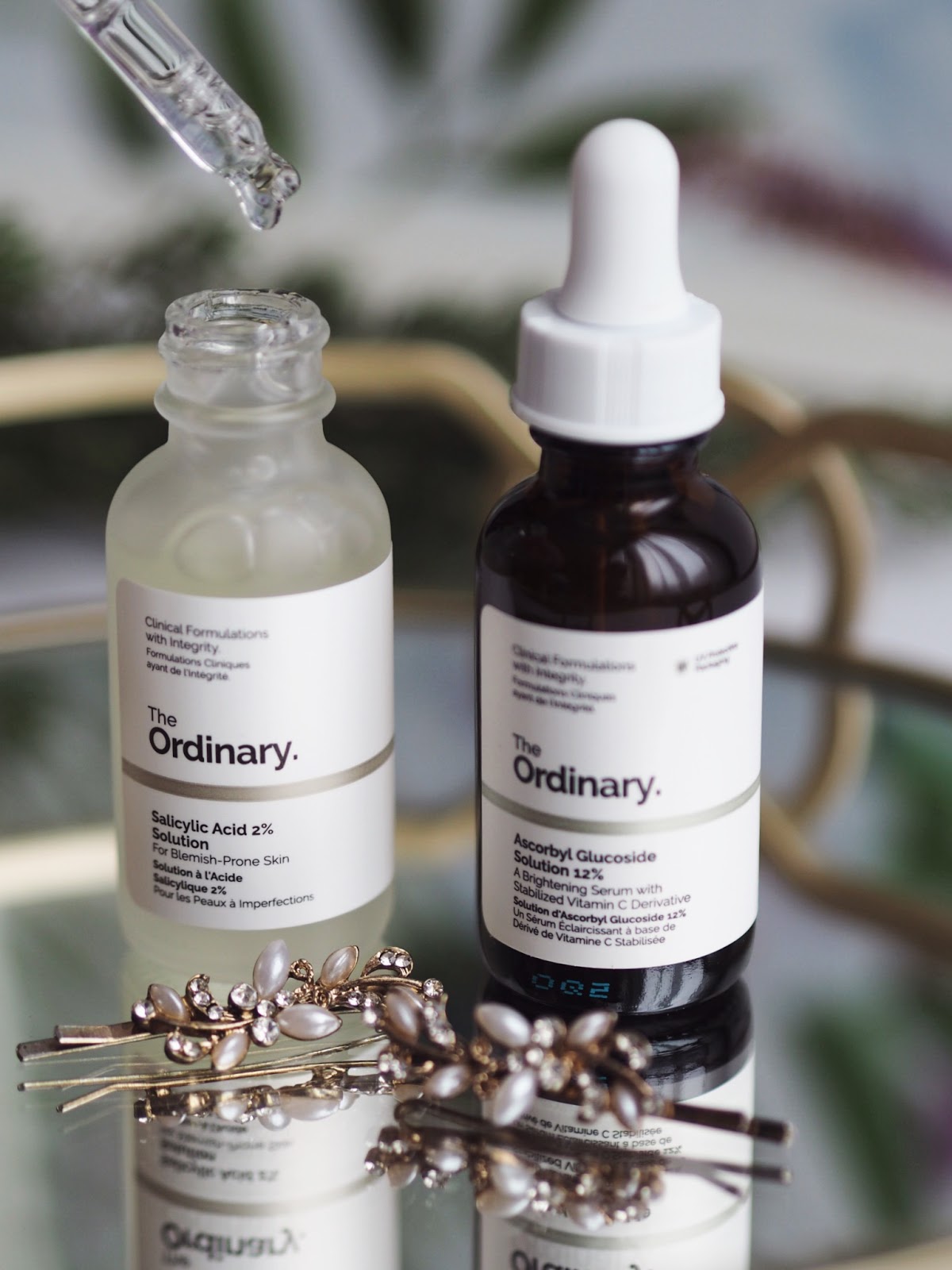 One clear bottle and one brown bottle of the ordinary skincare with the clear solution exposed with the droppe