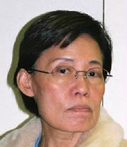 Headshot of a grim-expressioned middle-aged Korean woman wearing wire-rim glasses