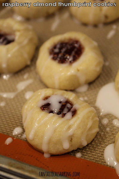 Raspberry Almond Thumbprint Cookies // These amazing shortbread cookies are filled with raspberry jam and drizzled with a sweet almond icing! #recipe #cookies #dessert #raspberry