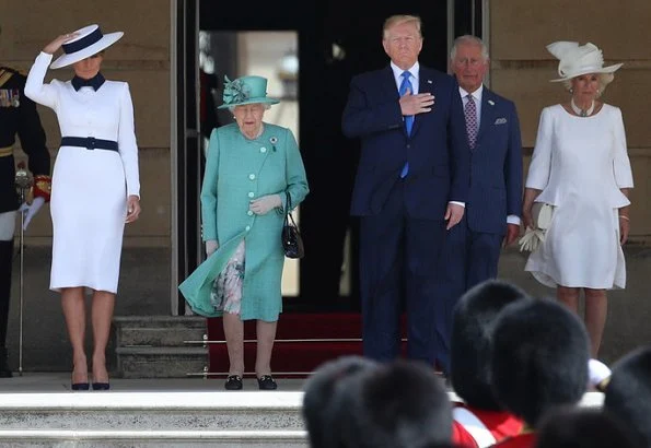 Melania Trump is wearing a custom white crepe dress with navy details by Italian fashion house, Dolce & Gabbana. Queen Elizabeth