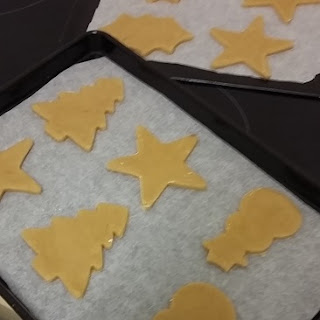 Picture of Christmas biscuits on greaseproof paper on top of the baking trays