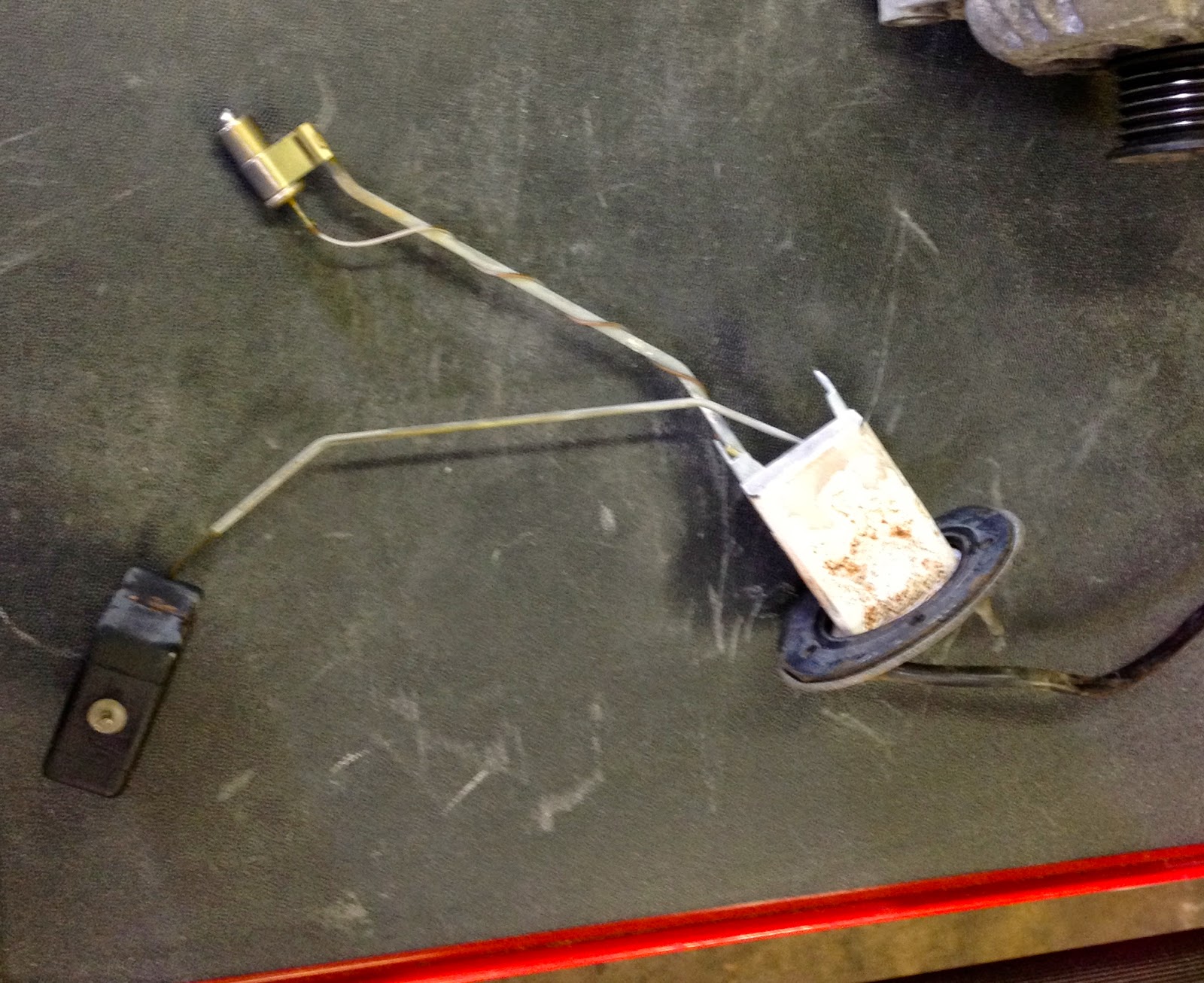 My fuel level sender after pulling it from the tank, it's covered with  white residue and rust. The little can on the bottom of the other metal rod  is for ...