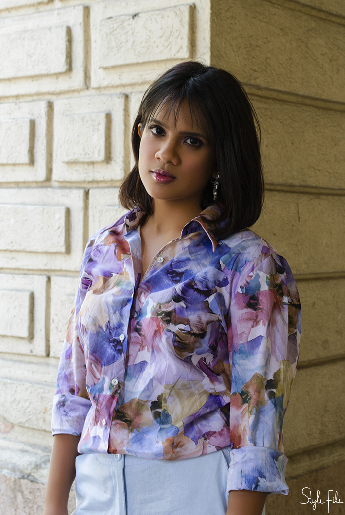 A female fashion blogger from India wears a pastel printed shirt with blue culottes and floral print high heels with dangling earrings, glossy lips and purple eye makeup for her fashion blog Style File 