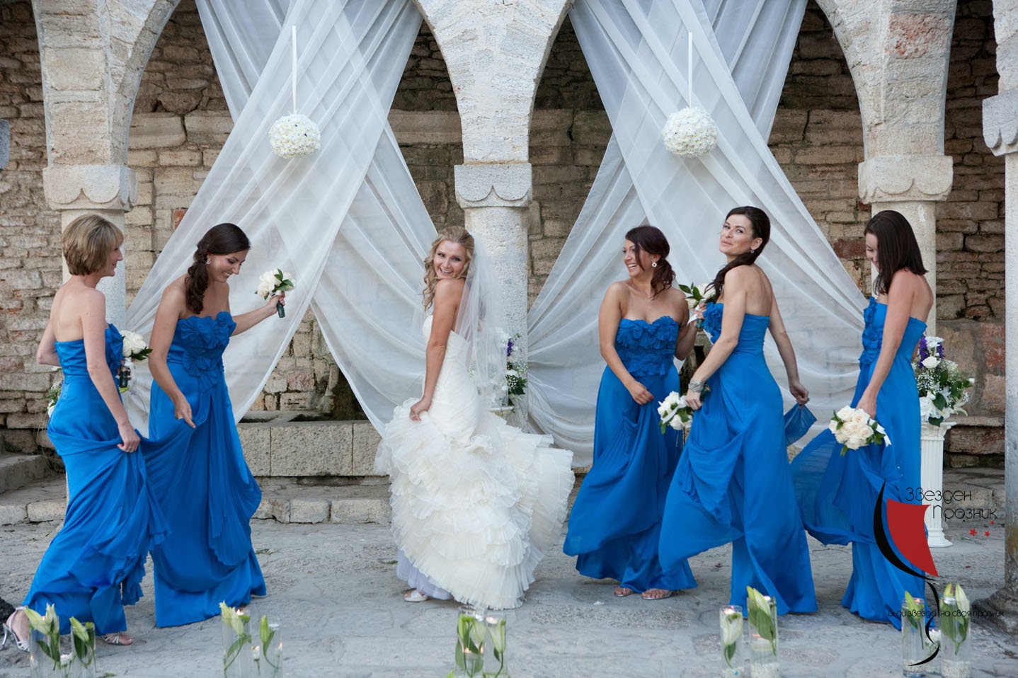 булката и шаферките с тъмно сини шаферски рокли се забавляват на фотосесията в Балчик