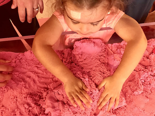 Toddler girl plays with pink kinetic sand