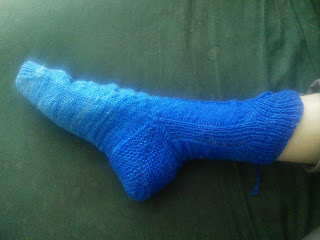 A gradient sock on someone's foot. The sock gradient runs from a deep royal blue at the cuff to a paler sky blue at the toe.