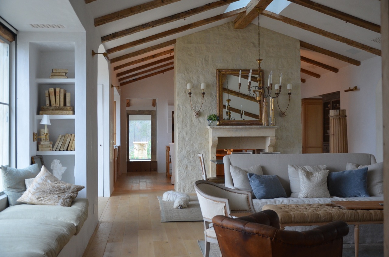 Patina Farm living room with linen, limestone fireplace, antiques, and window seat (found on Hello Lovely)