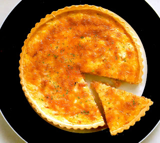 Classic quiche lorraine of a savoury egg custard containing cheese, shallots and bacon in a flaky pastry shell.