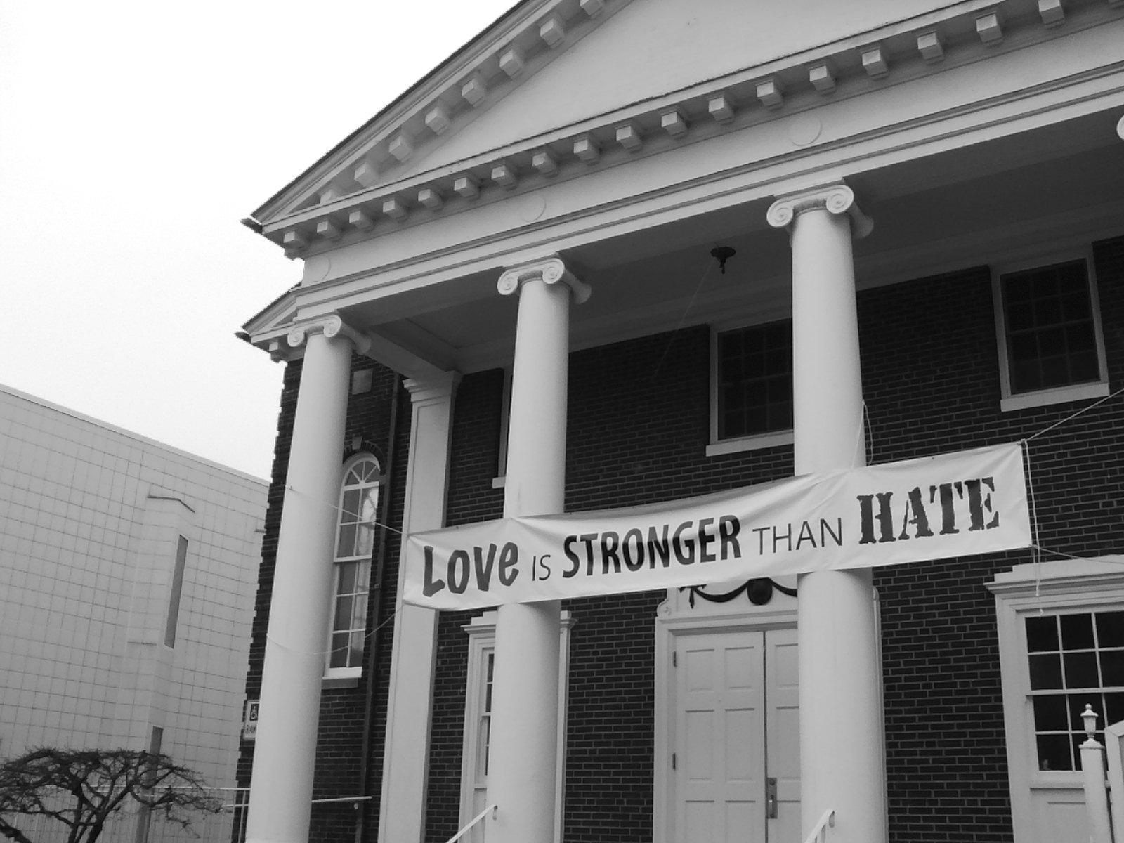 A banner over a building entrance says, 'Love is stronger than hate.'