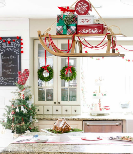 Vintage sled with presents hung over island in farmhouse style kitchen as Christmas decor