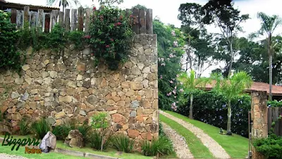 Muro de pedra construído com pedra moledo com o peitoril de dormente em cima.