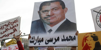 Protester with poster comparing Morsi and Mubarak