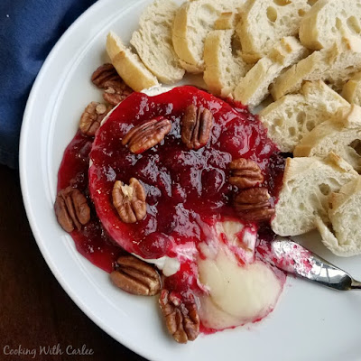 Gooey melty cheese is perfect for toasted bits of baguette. This maple cranberry baked brie is sweet and salty, tarty and gooey. It is perfect for a holiday or just because! melted brie spilling out of wheel and ready to be dipped in