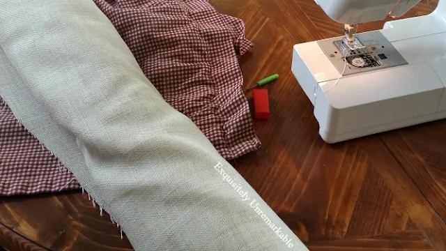 Linen fabric and red checked fabric next to sewing machine