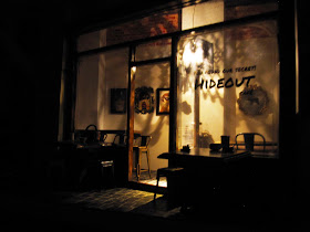 Exterior of a modern dolls' house miniature cafe at night, with the interior light up.