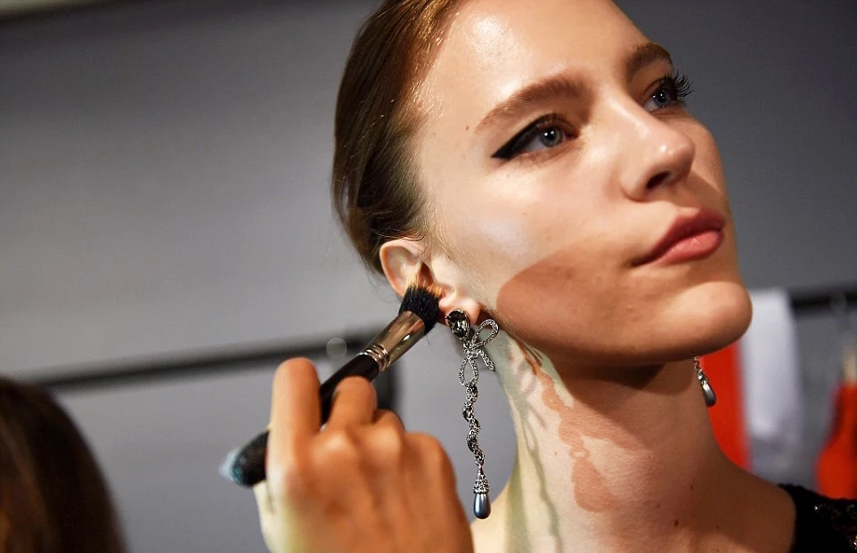 makeup artist applies makeup on to model's face