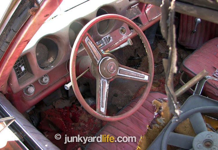 Red on red 1969 Cutlass S convertible interior has seen better days when discovered at an Alabama scrap yard.