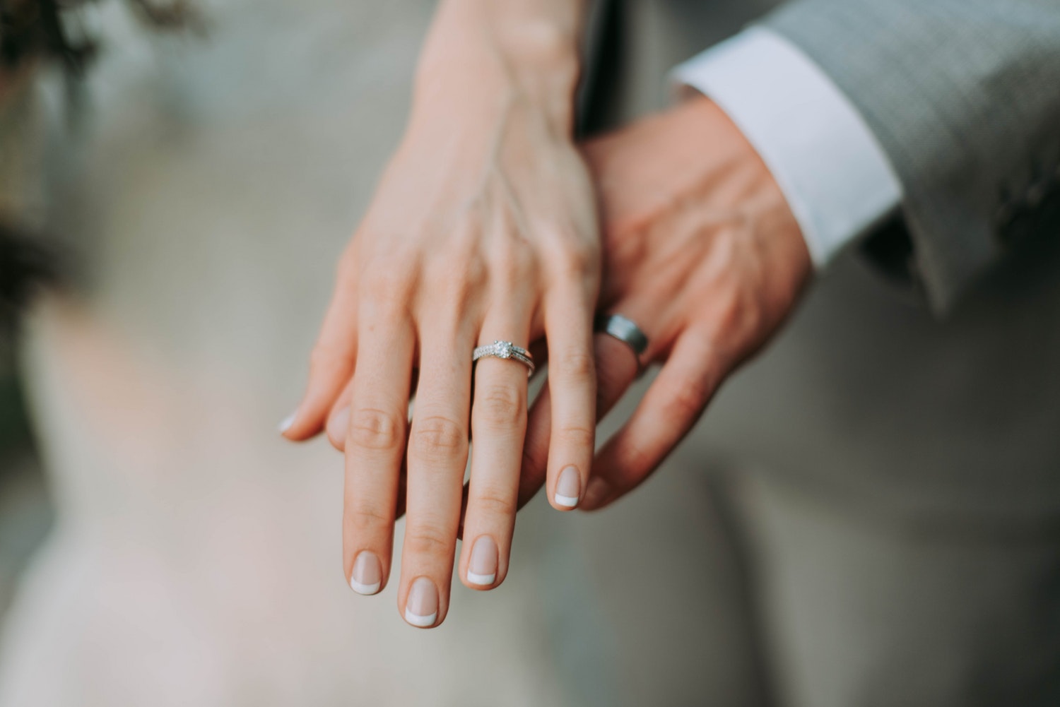 close-up of groom's and bride's hands holding each other and wearing rings