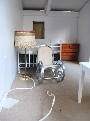 Modern dolls' house miniature floor lamp next to a rocking chair in a dry-fitted miniature kit shed.