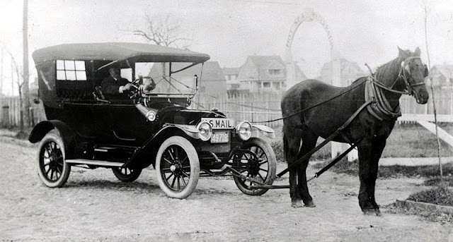 Clinton Folger's "Horsemobile" delivering mail, on South Beach Street, at Hayden's Bath House entrance. For nearly twenty years, from 1900 to 1918, Nantucket was the only place in the nation that successfully fought encroachment of the automobile within its limits. Opposing politicians on the mainland and large property owners, mostly non-residents, Nantucketers kept the island free of the "gasoline buggy" until the final vote of the town on May 15, 1918. By the narrow margin of forty the automobile was allowed entry. Clinton Folger was the mail carrier for Nantucket. Because cars were forbidden by the town, he towed his car to the state highway for driving to Siasconset. Source: Nantucket Historical Association