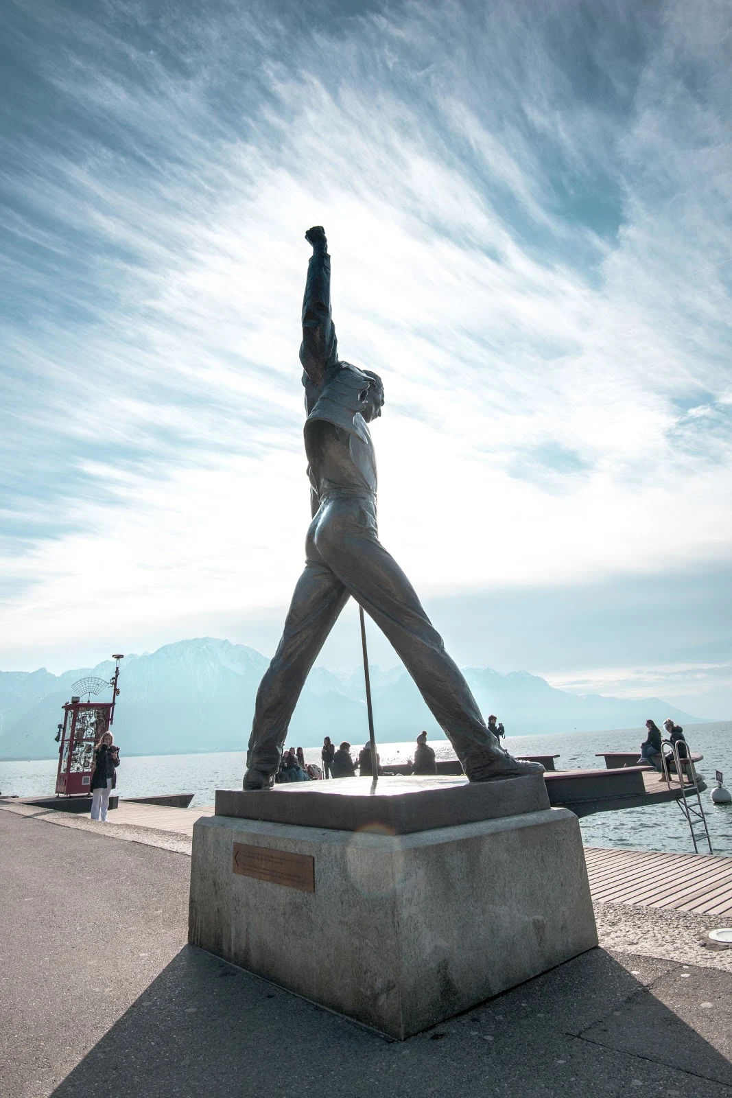 スイスのモントルーのレマン湖の畔の両足を開いて右手を上げたフレディ・マーキュリーの銅像