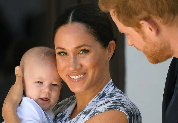 Meghan Markle wore Clup Monaco dremah silk midi dress and Everlane essential goweave jumpsuit. Gas earrings