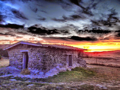 A sod house with a beautiful sunset in the background