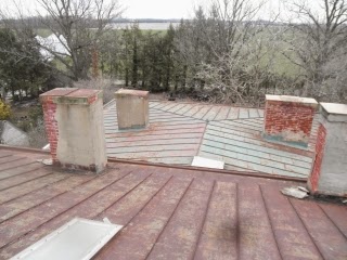 Grey metal roof project before work started on the panels, inside gutters and six large chimneys