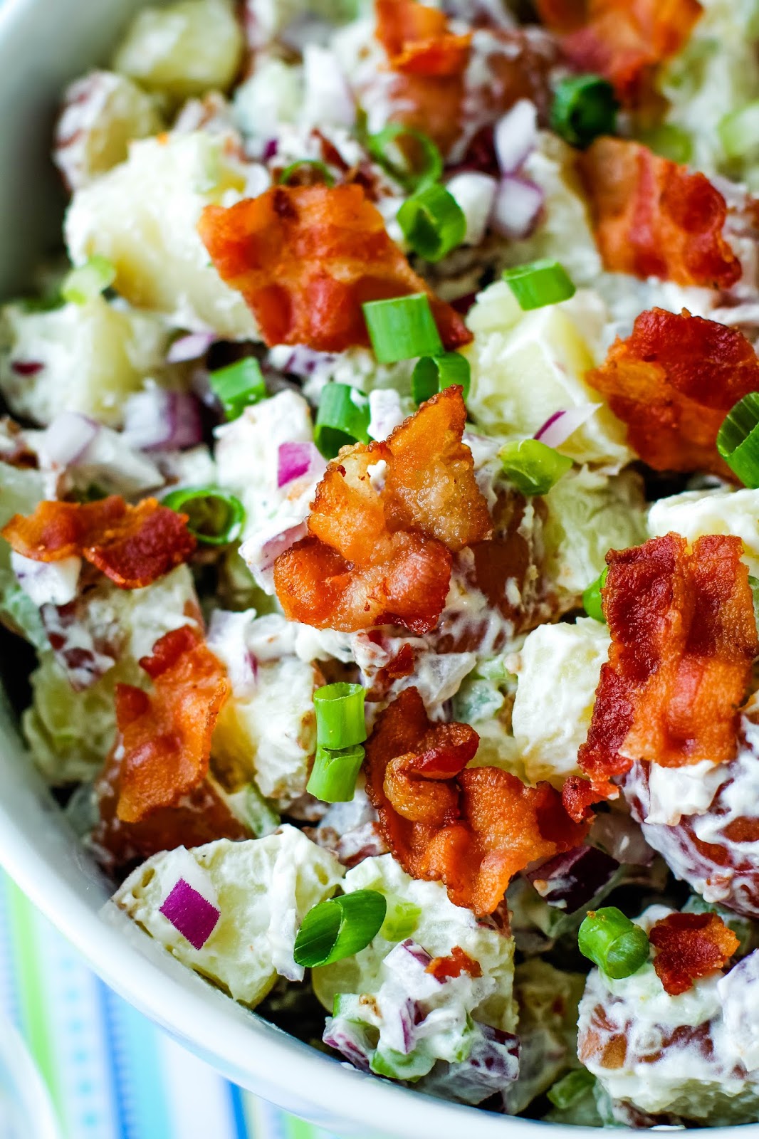 Red Potato Salad with Bacon is made with a cool and creamy mayo-sour cream mixture and tons of crumbled bacon. This simple side dish is perfect for barbecues, parties, and tailgating! #potatosalad #sidedish #bacon