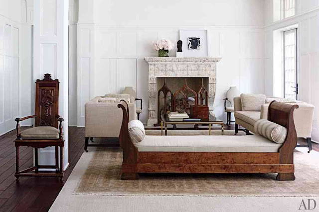 Living room with restaind wood floor and a high back bench with a white cushions, a marble fireplace and dueling sofas