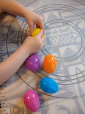 preschooler shaking the eggs to listen and find out what's inside